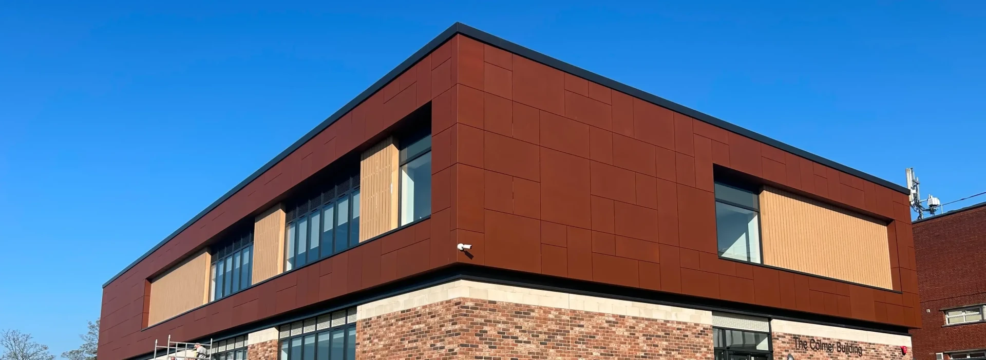 The cromer building, a modern style with dark red cladding, with blue sky behind it.