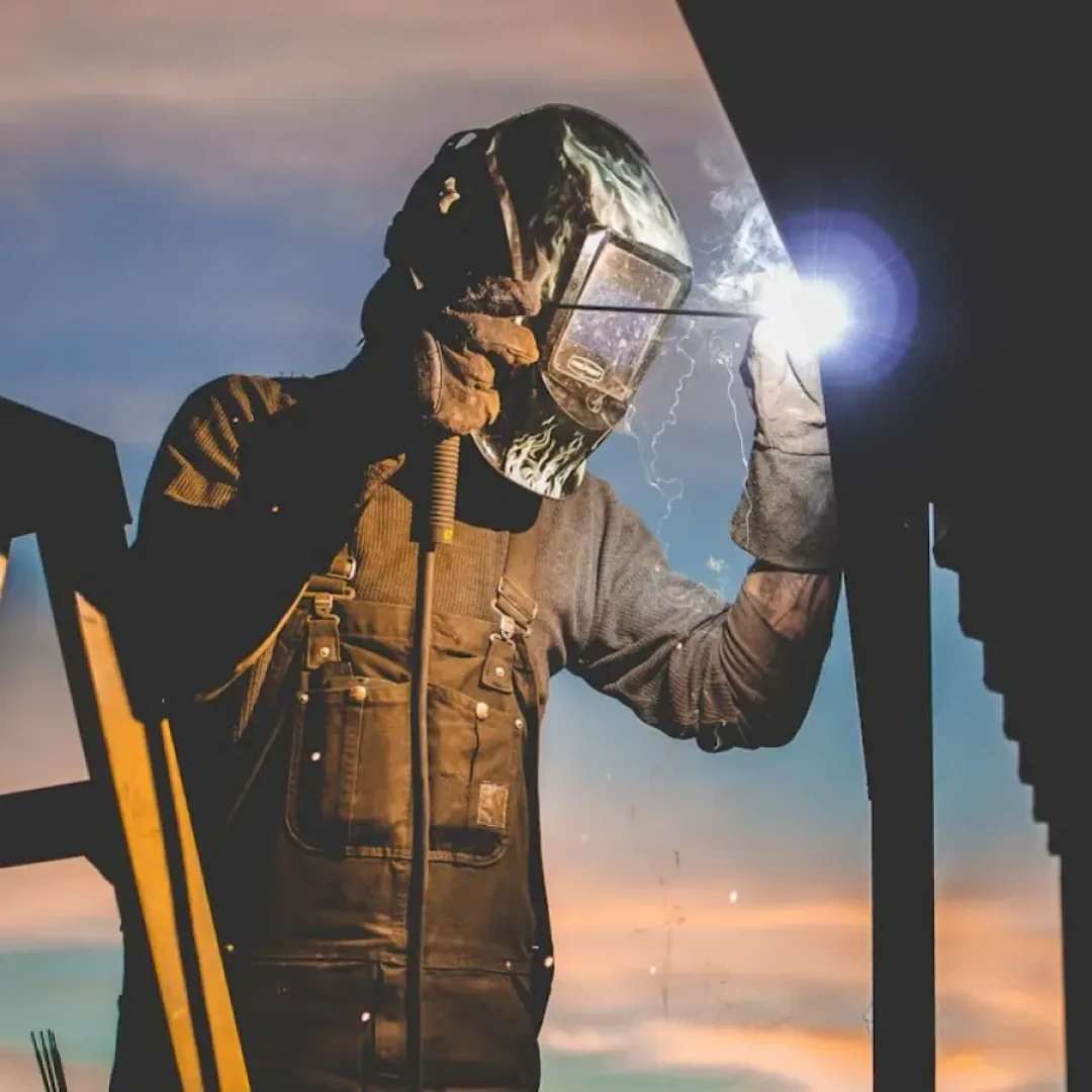 A person with visor, doing welding on a building.