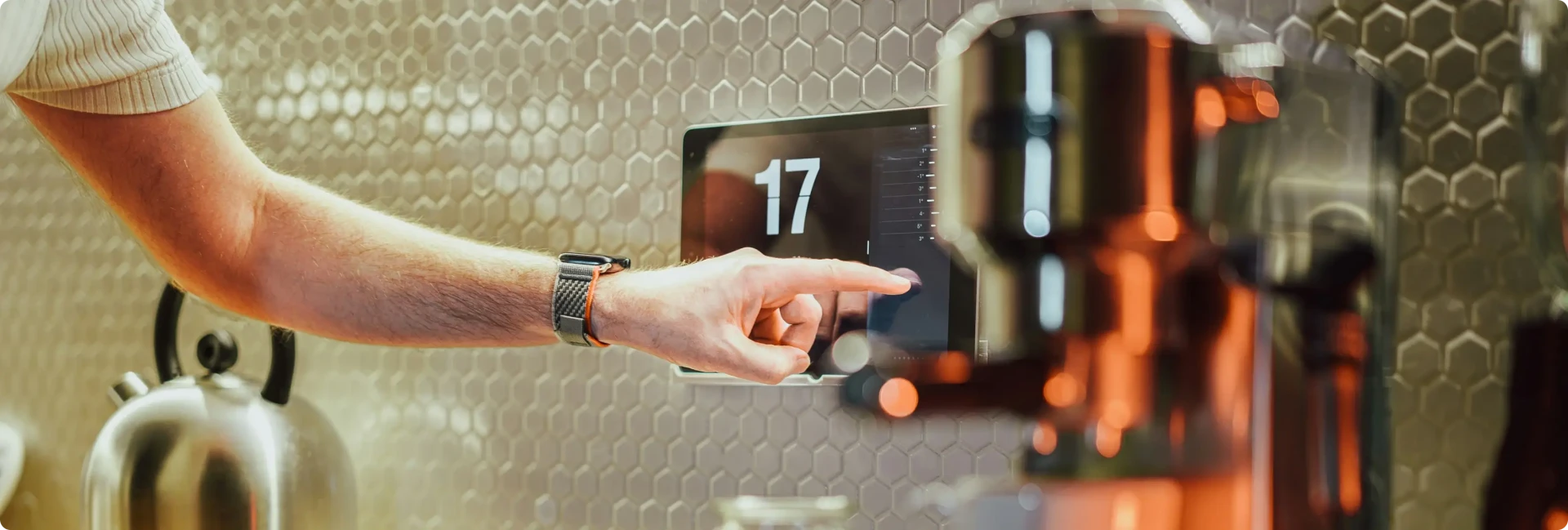 A person interacts with a smart home control panel, in a trendy modern kitchen.