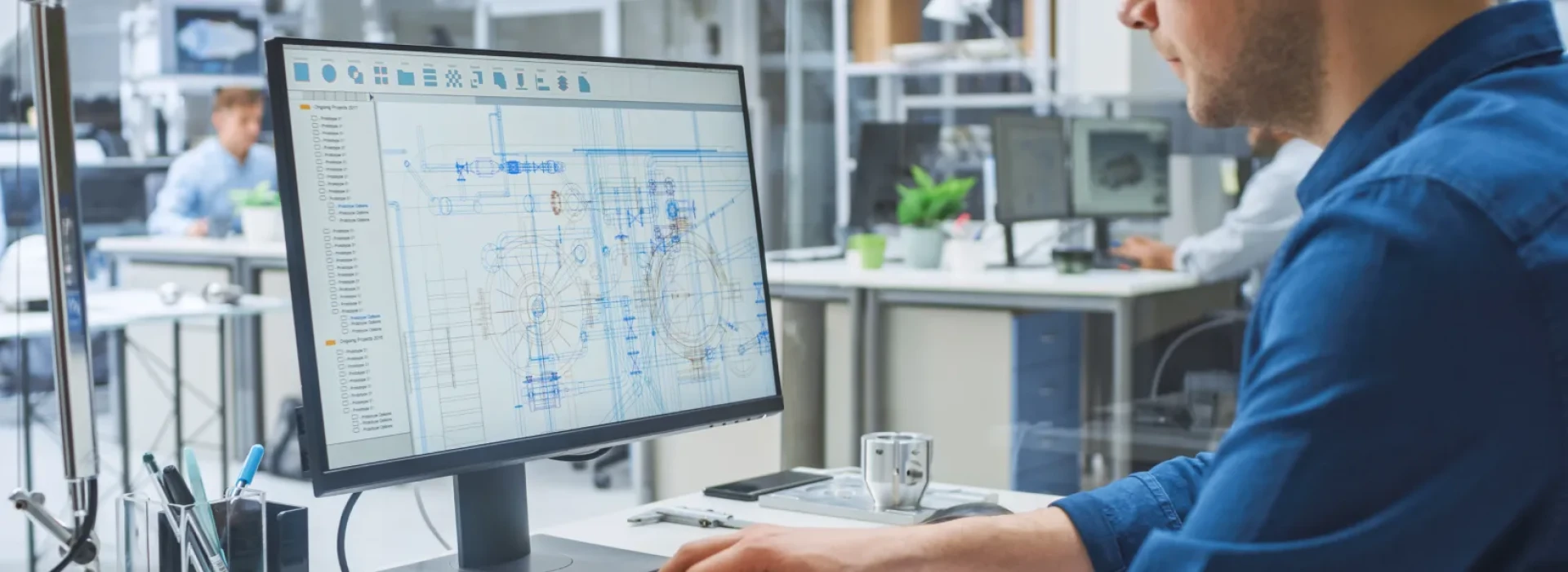 An engineer is designing on a CAD programme, on a computer, in an office.